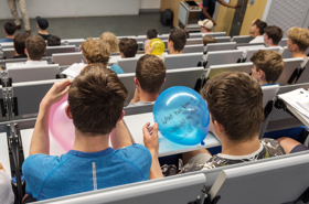 Students in lecture theatre writing questions on balloons