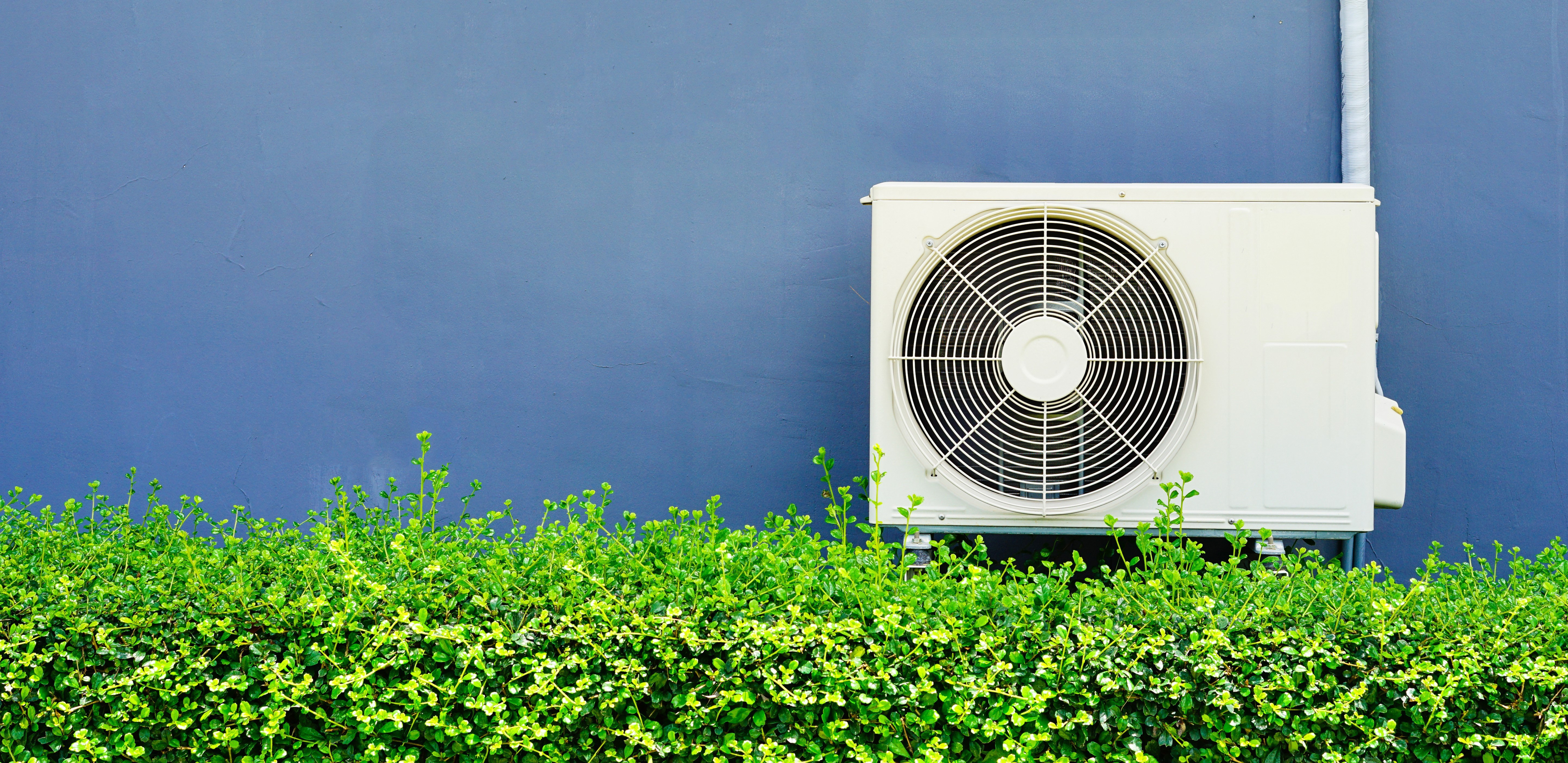 An air conditioner set against a blue wall.